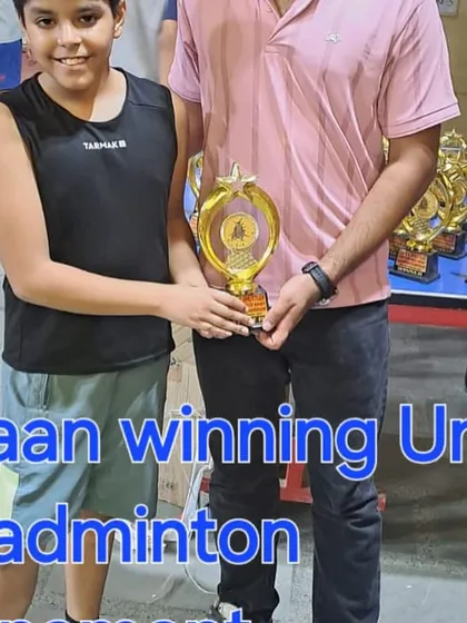 Coach presenting Yuvaan with his trophy for winning the Under-11 badminton tournament. We focus on developing competitive players from a very young age.