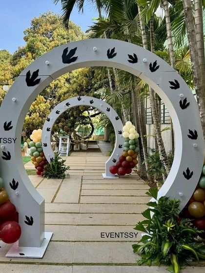 A creative entranceway using large arches with dinosaur footprints, leading guests into the prehistoric party zone.