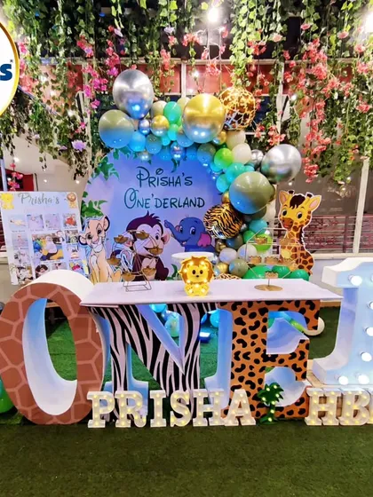 We transformed this space into a lush jungle for Prisha's "Onederland" party. The setup includes a large 'ONE' table with animal-print lettering, character cutouts of a leopard and zebra, and a backdrop of hanging foliage, creating a truly immersive wild animal adventure.