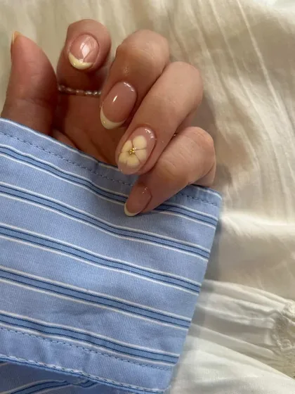 A close-up of the dainty flower detail that adds a personal and charming touch to this classic French manicure.