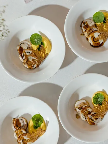 Four small plates of chicken roulade, ready for service. The consistent and beautiful plating across all dishes is a hallmark of our commitment to quality, even for large events.