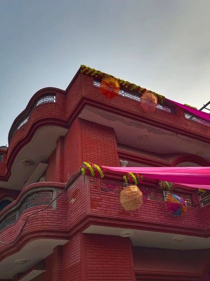 An angled shot of a house decorated with pink drapes and hanging baskets and umbrellas. This shows how I use different elements to create a unique look.
