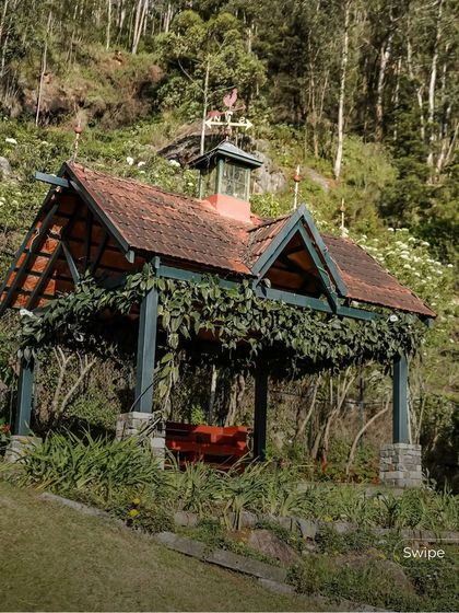 A charming gazebo covered in vines provides a shaded outdoor seating area, blending perfectly with the lush garden landscape.