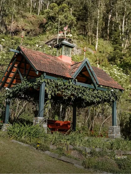 A charming gazebo covered in vines provides a shaded outdoor seating area, blending perfectly with the lush garden landscape.