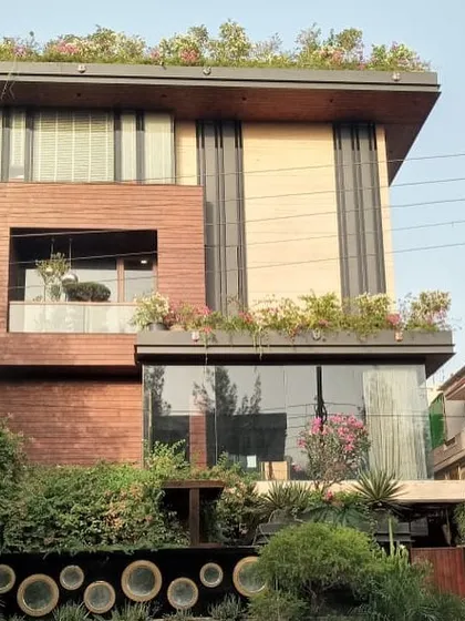 A full view of the multi-level home, showing how the rooftop garden, balcony plants, and extensive ground-level landscaping work together to create a cohesive, green architectural statement.