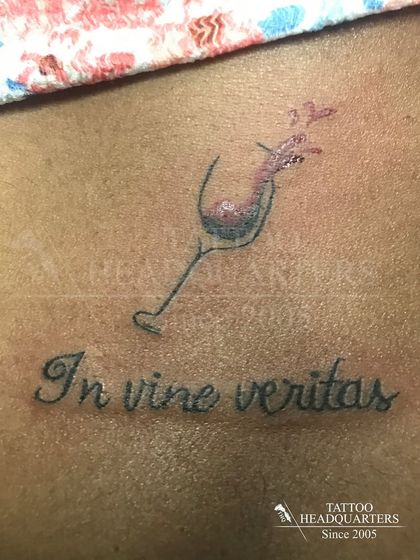 The Latin phrase "In vino veritas" ("In wine, there is truth") tattooed with a splashing wine glass.