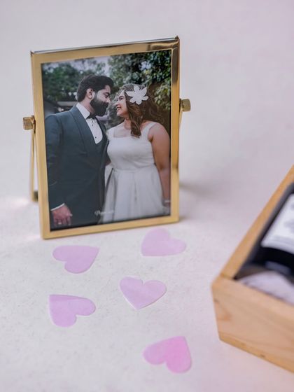 The couple's photo frame is shown with scattered heart confetti, enhancing the romantic and celebratory feel of the gift.