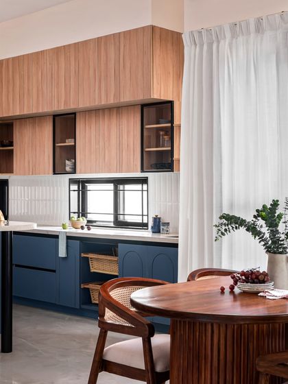 This open-layout kitchen features a striking combination of deep blue and warm wood-toned cabinets. I used arch grooves on the lower shutters to add character, and a compact island counter provides extra workspace and storage.