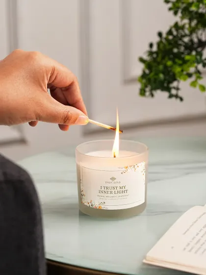 A lifestyle shot showing a hand lighting a scented candle, creating a relatable and aspirational moment. We believe showing products in a real-life context helps customers envision them in their own homes, which is key for conversion.