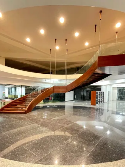 The main atrium at Rishihood University, Sonipat, featuring a sculptural wooden staircase and polished marble floors. This space is designed as a central hub, connecting different parts of the campus and fostering a sense of community.