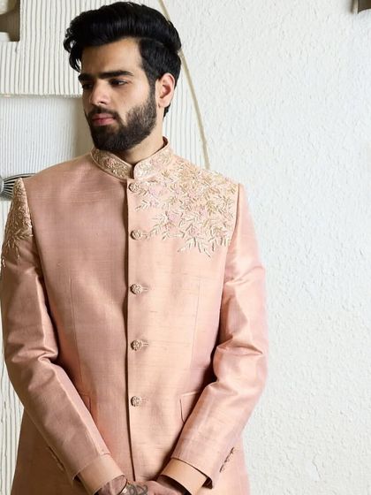 A full view of the baby pink bandhgala suit. The soft, elegant color and minimal threadwork make it a perfect choice for a summer wedding.