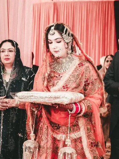 The bride's entry during a Sikh wedding ceremony, accompanied by her parents.