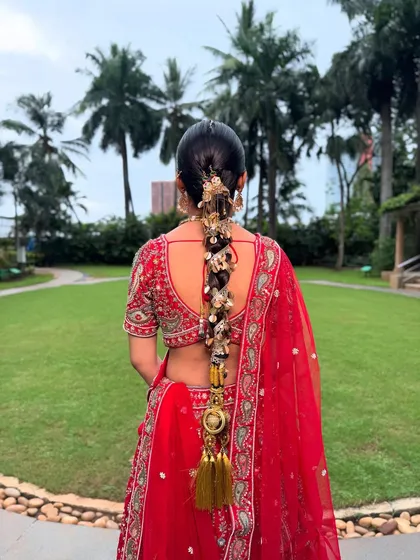 For this bride, we created a statement look with a traditional long braid, or 'choti', heavily adorned with stunning gold accessories. This style is perfect for framing an ornate lehenga and ensuring you look regal from every angle.