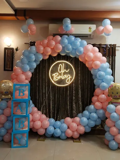 I can transform any room in your home into a beautiful celebration space. Here, I created a classic pink and blue circular balloon arch with an "Oh Baby" neon sign, perfect for an intimate at-home baby shower.