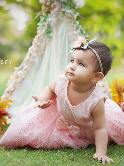 A baby girl exploring the grass during her outdoor photoshoot. The soft, golden light of the afternoon creates a magical glow.