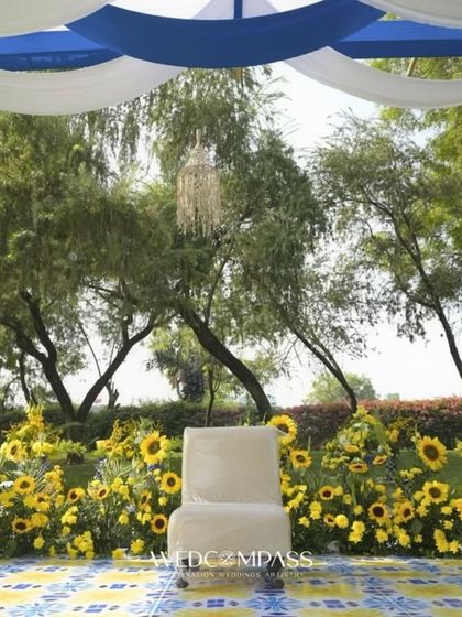 A minimalist haldi seating area with a single chair against a wall of sunflowers. The simplicity of the setup highlights the natural beauty of the flowers and the outdoor setting.