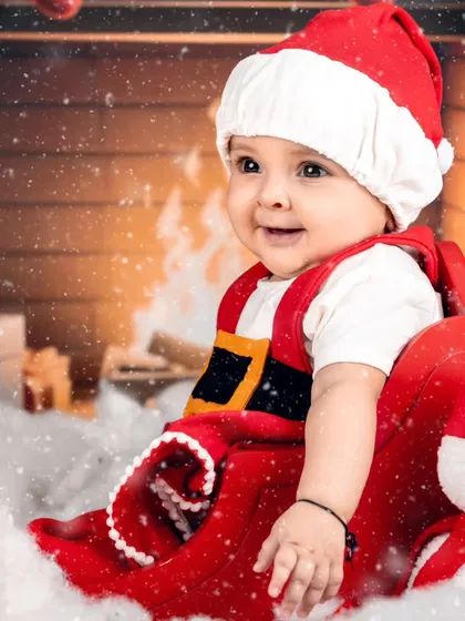 A cozy Christmas scene with a baby Santa and his snowman friend by the fireplace.