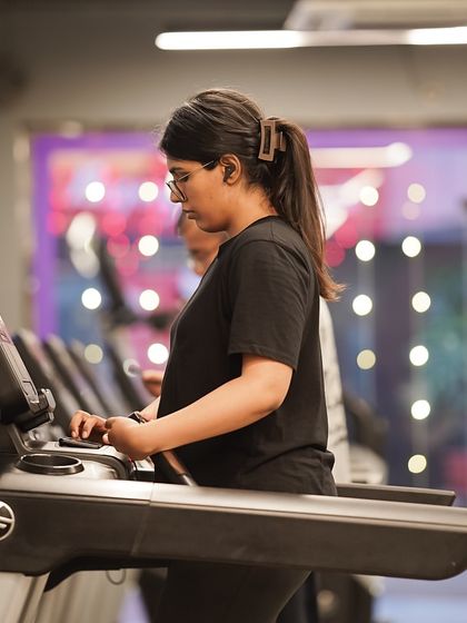 A member focuses on her run, using one of the many treadmills available in our spacious cardio section.