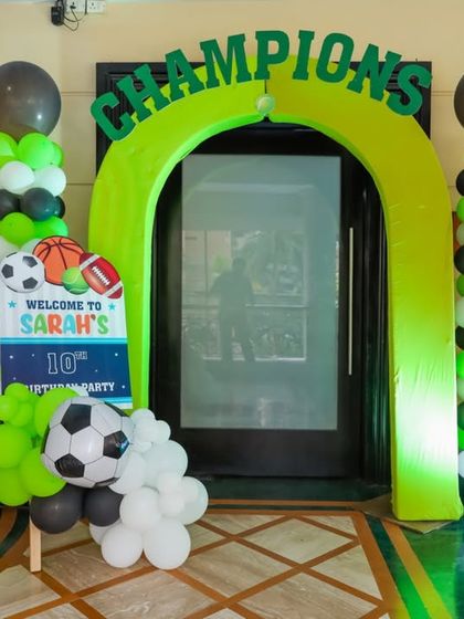 A "Champions" archway for a sports-themed party, decorated with green, black, and white balloons and a soccer ball accent.
