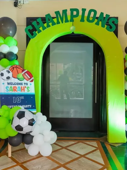 A "Champions" archway for a sports-themed party, decorated with green, black, and white balloons and a soccer ball accent.