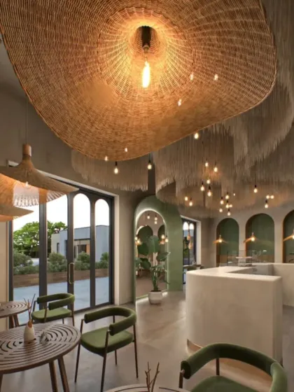 This view shows how the cafe opens up to an outdoor space, blurring the line between indoors and outdoors. The consistent use of natural materials and green tones creates a cohesive, tranquil environment.
