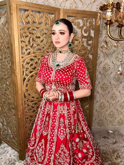 A full-length shot of the bride, showing how the heavy jewelry perfectly balances the richly embroidered red lehenga.