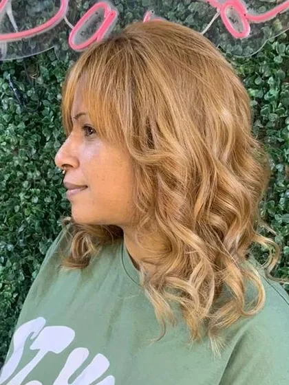 A side profile of the rose-gold global color, showing how it complements the client's skin tone and the soft wave styling.