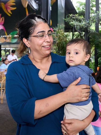 A mother holding her baby, surrounded by the calm and green atmosphere of the venue.