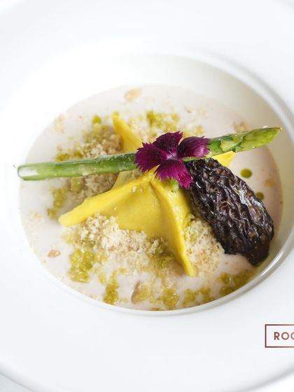 A top-down view of the Butternut Squash Manti. The parmesan yakhni provides a savory, umami-rich broth that perfectly complements the sweetness of the butternut squash filling.