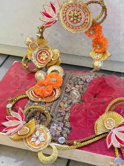 Another example of my detailed trousseau work. A deep red embroidered outfit is laid out on a wooden tray and adorned with handcrafted lotus and floral embellishments made from gota fabric.