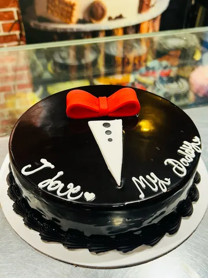 A simple yet sweet chocolate truffle cake with a tuxedo collar and bow tie design, saying "I love My Daddy".