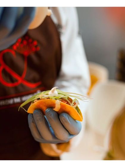 A chef carefully assembles a miniature taco, adding a final drizzle of sauce. This close up highlights the handmade, artisanal quality of our appetizers.