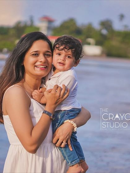 A mother holds her son close, her smile radiating pure love and happiness. This candid portrait by the sea is a beautiful testament to the strong bond they share.