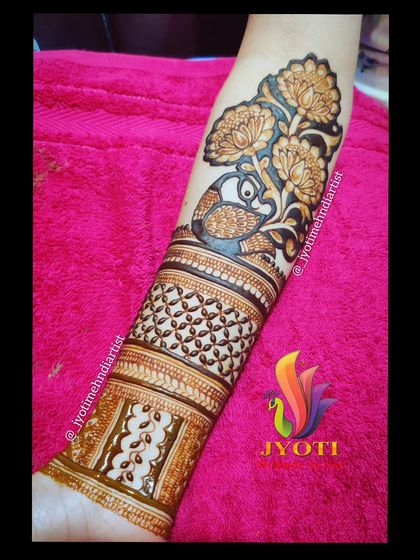 A bridal startup design showing a peacock amidst a garden of flowers on the upper arm. This is often the beginning point from which the rest of the arm's design flows.