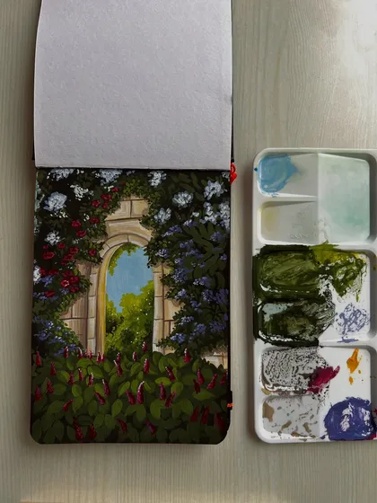 A gouache painting of a secret garden archway, with my paint palette alongside.