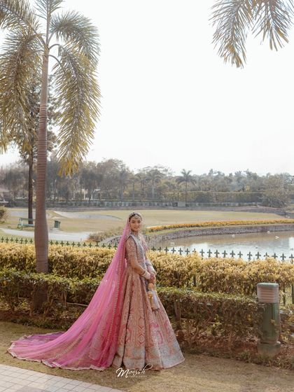 A beautiful solo portrait of the bride in a picturesque outdoor setting, her long veil adding a touch of fairytale romance.