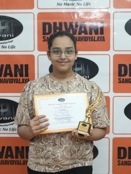 A student proudly holds her certificate and trophy.