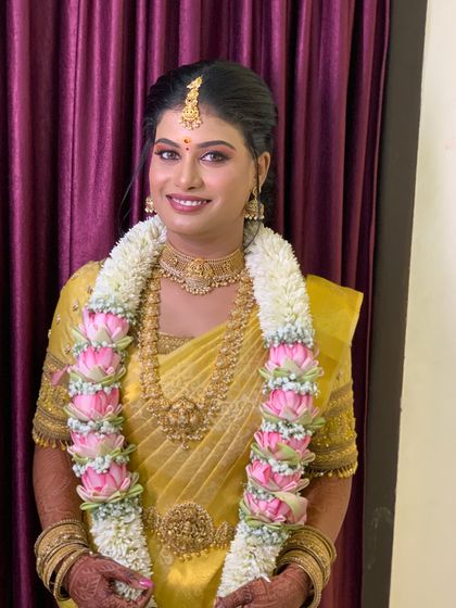This bride is glowing in her golden yellow Muhurtham saree. The drape is kept classic and neat to let the saree's colour and the temple jewellery shine.