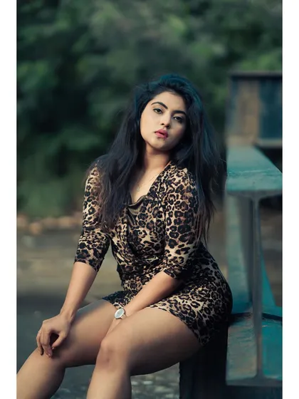 An outdoor portrait with a wild, untamed feel. The animal print dress and the natural, slightly messy hair work perfectly with the lush green background.