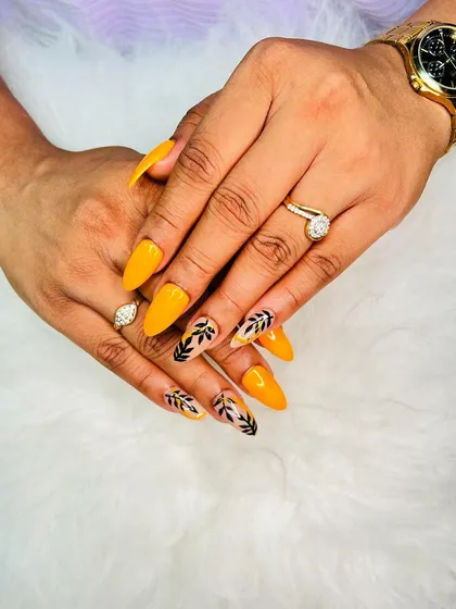 A bright and cheerful set of yellow stiletto extensions with black leaf art on the accent nails.