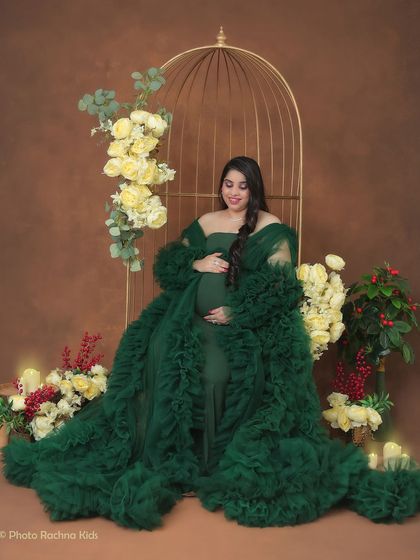 A peaceful moment captured in our elegant birdcage chair. The rich green gown and surrounding floral arrangements create a lush, garden-like atmosphere.