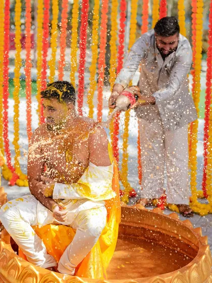 The groom gets a drenching during his Haldi ceremony. We love capturing the playful side of wedding rituals, where friends and family show their love in the most fun ways possible.