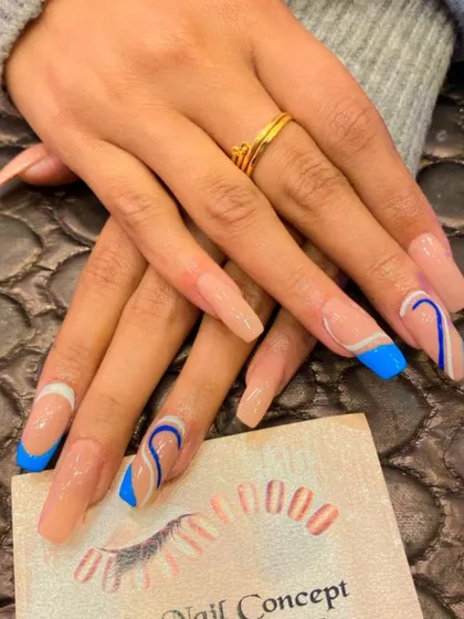 A modern and artistic design on long, square nails. The nude base is decorated with a mix of blue French tips and abstract blue and white swirls.