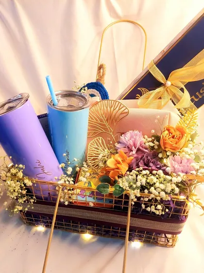 A beautiful wedding gift hamper for a lovely couple. This basket includes personalized sippers, grooming products, and other goodies, all decorated with flowers and baby's breath.