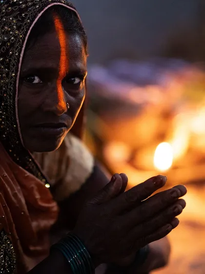 A woman offers her prayers during the Chhath Puja festival in Delhi. The warm glow from the diyas illuminates her face, highlighting a moment of deep, personal faith amidst the communal celebration.