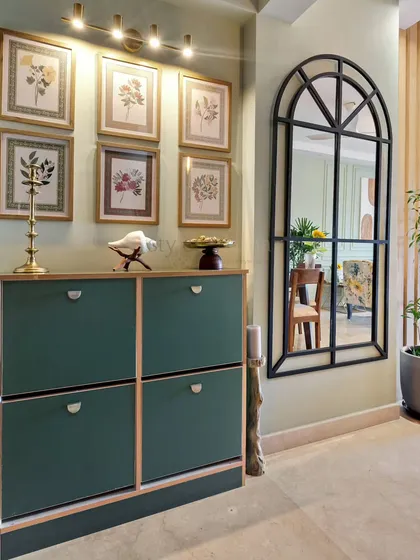 A stylish foyer with a dark green shoe cabinet, an arched black metal mirror, and a gallery wall of botanical prints. This entryway is both functional and beautifully curated, setting a sophisticated tone for the home.