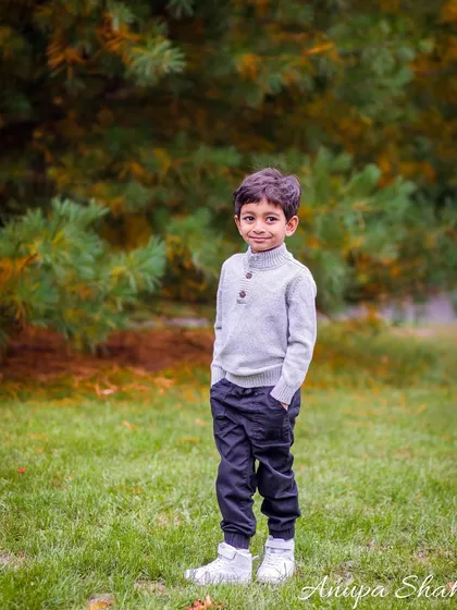 A handsome portrait of a young boy posing confidently in a park. This shot captures his personality and style during a family maternity session.