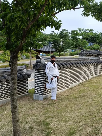Leaning against a traditional Korean wall, a blend of modern training and ancient culture.