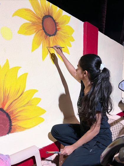 Painting the large yellow sunflowers, making sure they stand out boldly against the deep blue night sky.