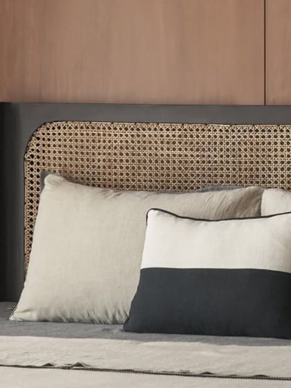 A detail shot of the custom black bed with a woven rattan headboard. The mix of black and natural cane creates a striking contrast that is both modern and timeless.